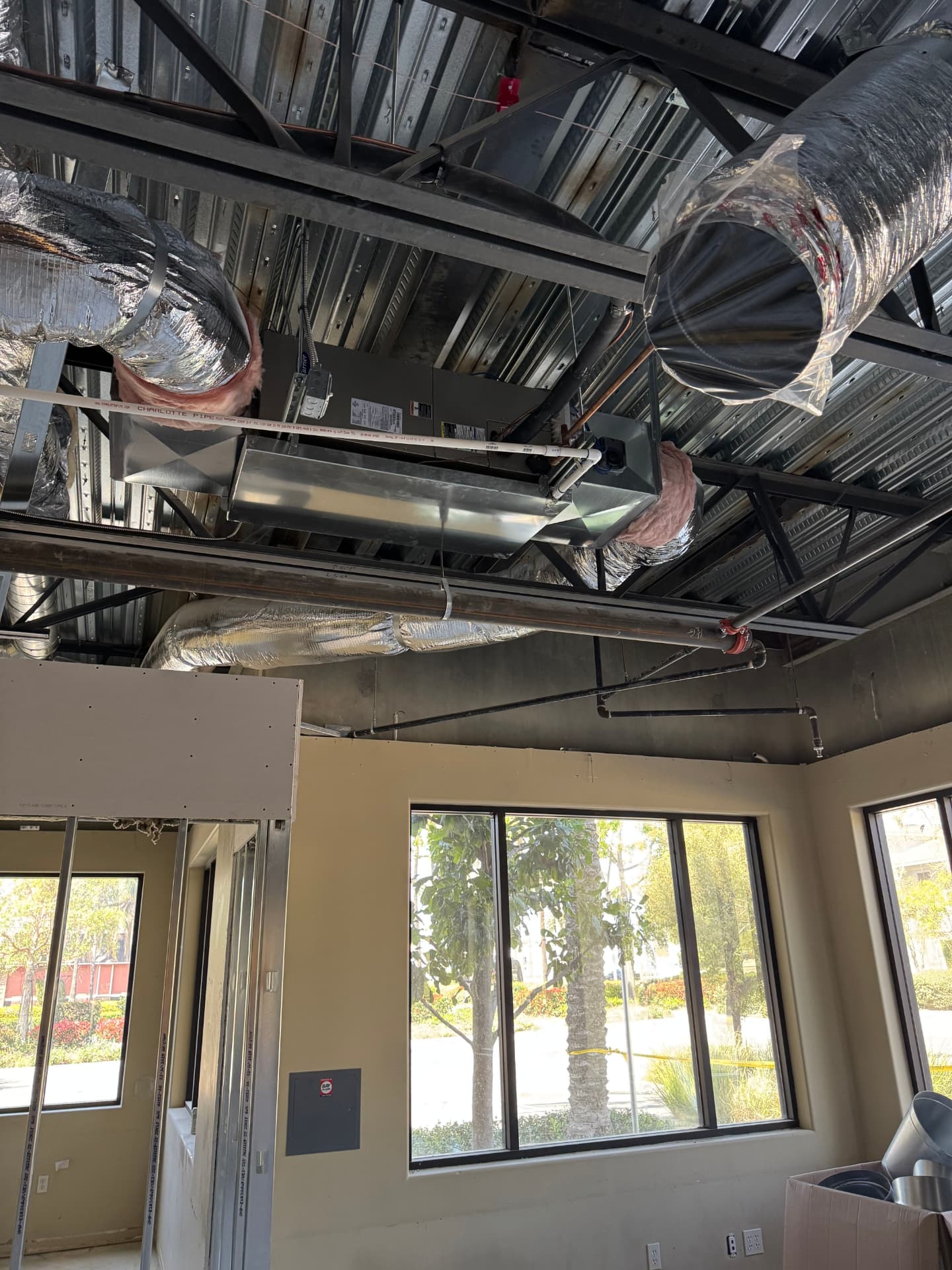 Commercial HVAC unit and duct trunk installed above an open ceiling in a tenant space